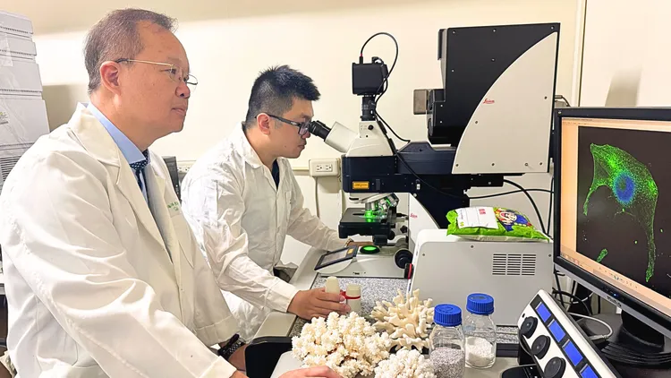 中山大學海洋生物系特聘教授溫志宏與生醫所博士生張瓏，與鹿角珊瑚骨骼。中山大學提供