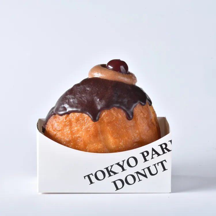 東京巴黎甜點5款生甜甜圈新品，「酒漬櫻桃巧克力」售價98元，內餡以酒漬櫻桃與72%巧克力製成，再加入生乳柔化口感，交織出深邃可可風味與果香酒韻，微醺成熟風味，苦甜適中不膩口，完美滿足大人系甜點味蕾。業者提供