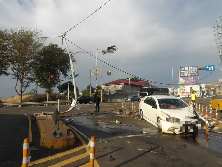 黃男猛撞路口分隔島，號誌桿被撞到扭曲變形，殘骸、零件散落一地。民眾提供