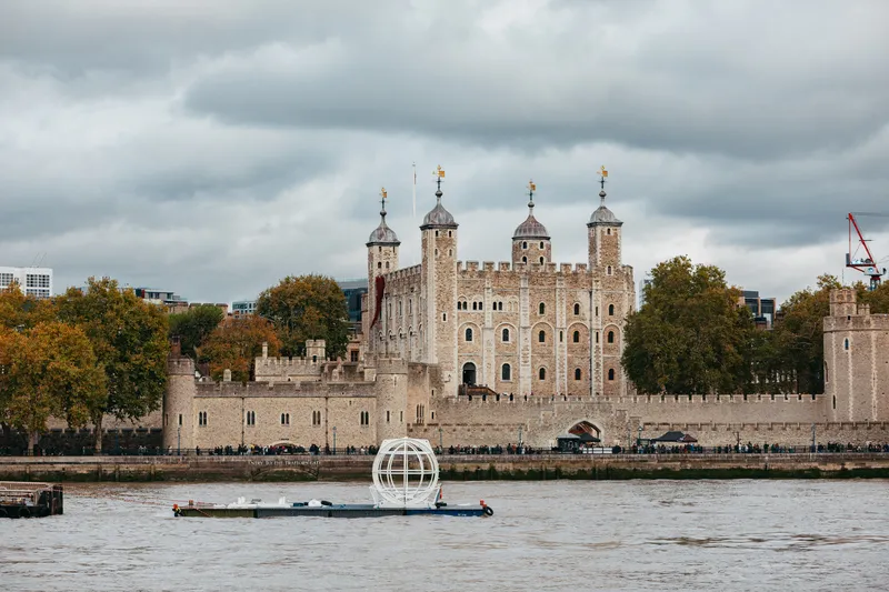 「伦敦眼」摩天轮预计至2029年执行座舱更新升级工程，期间将陆续有卸下的座舱沿著泰晤士河被运往工厂受检施工。图为被卸下的座舱途经伦敦另一知名地标「伦敦塔」古堡。（伦敦眼提供） 中央社