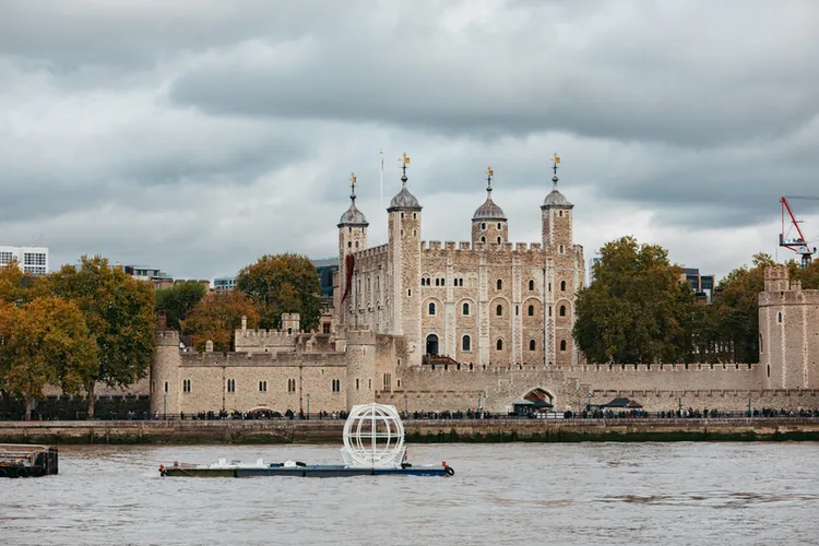 「倫敦眼」摩天輪預計至2029年執行座艙更新升級工程，期間將陸續有卸下的座艙沿著泰晤士河被運往工廠受檢施工。圖為被卸下的座艙途經倫敦另一知名地標「倫敦塔」古堡。（倫敦眼提供） 中央社