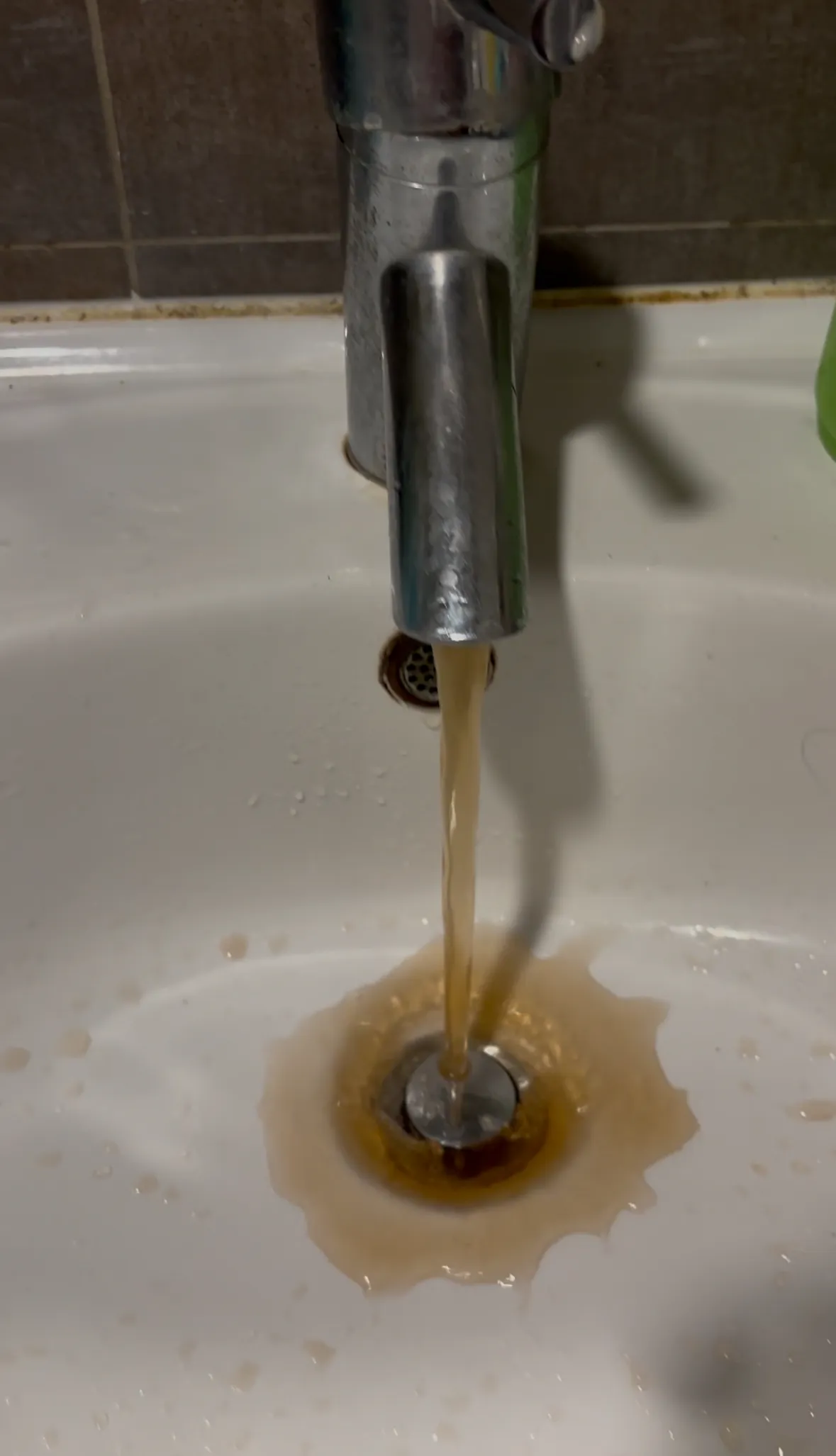 淡水區復水後，民眾家中水龍頭流出帶有泥沙的褐色水。邱筠媜攝