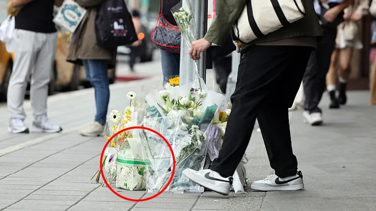 民眾20日在誠品南西店外人行道獻花哀悼昨晚隨機砍人事件罹難者，其中出現一袋UG TEA手搖飲（紅圈處），引發網友反感。中央社