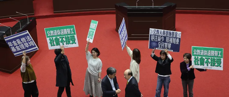 立院三讀通過公務人員退撫法修正，綠營立委在議場內舉牌表態。中央社