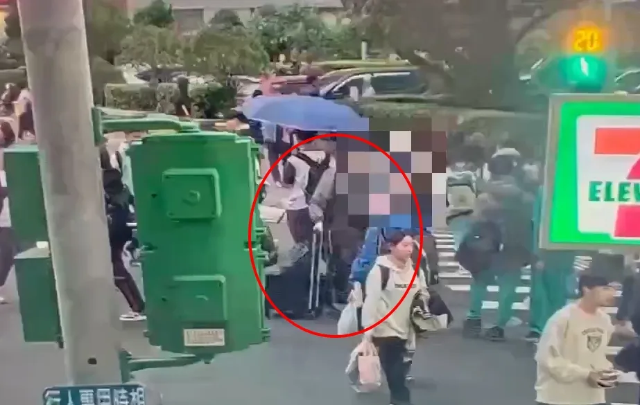 张文穿雨衣走过街头。翻摄画面