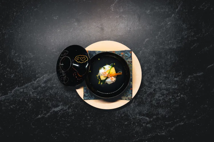 椀物以伊勢龍蝦為主軸，搭配金時人參、白蘿蔔與象徵共生長久的「相生結」，呈現日本正月的紅白祝福意象，將祈念寄於暖湯之中。亘一郎提供