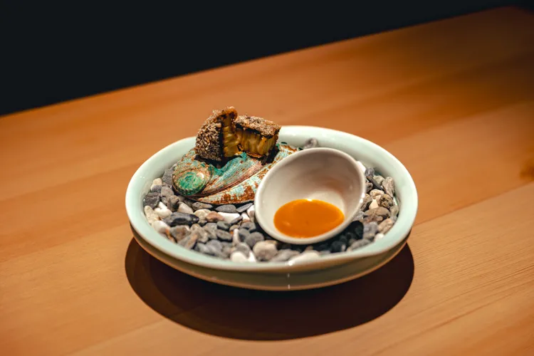 炸物選用冬季風味最佳的台灣九孔鮑，先蒸後炸使鮑魚柔軟中帶微酥，以蒸製海膽醬增添風味深度，呈現「擇優在地」的冬季旬味。亘一郎提供