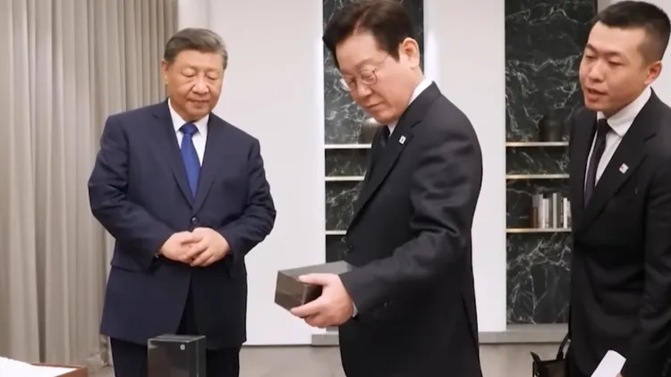 中國國家主席習近平（左）致贈韓國總統李在明（中）小米手機，李在明表情微妙詢問，「通訊安全如何」。翻攝微博/韓國APEC致贈禮物
