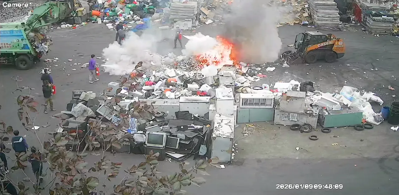 垃圾車斗倒出之垃圾堆擴大燃燒，環保人員拿乾粉滅火器進行初期滅火。翻攝畫面