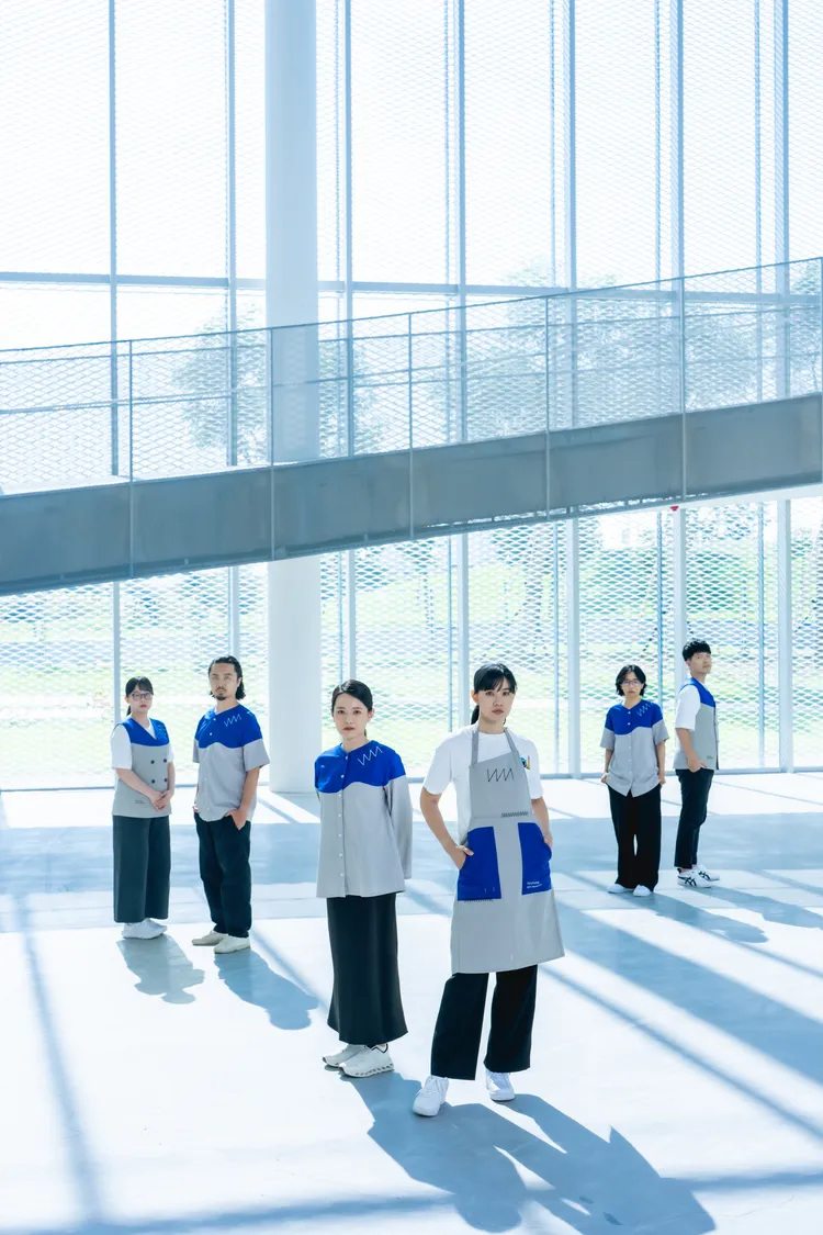 美術館的工作服透過藍色不規則墨流色塊，象徵著藝術不被框架束縛的純粹靈魂。品牌提供