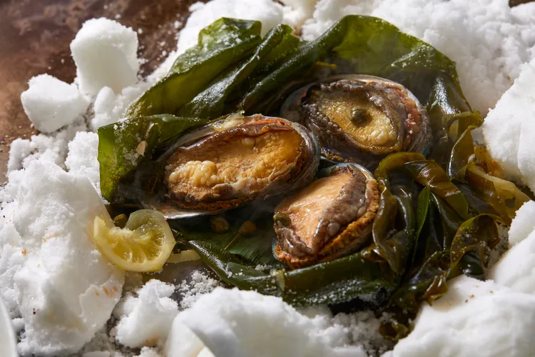 「鹽蒸鮑魚」是  Ukai  鐵板燒料理中傳承逾 40 年的經典招牌菜。以細緻的鹽層包覆鮑魚，以低溫緩慢蒸煮，完整保留海味鮮甜。The Ukai Taipei提供