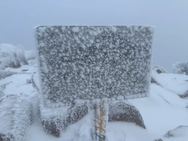 玉山降雪持續，地標告示牌幾乎被白雪覆蓋，連字跡都被遮住，現場一片銀白雪景。氣象署提供