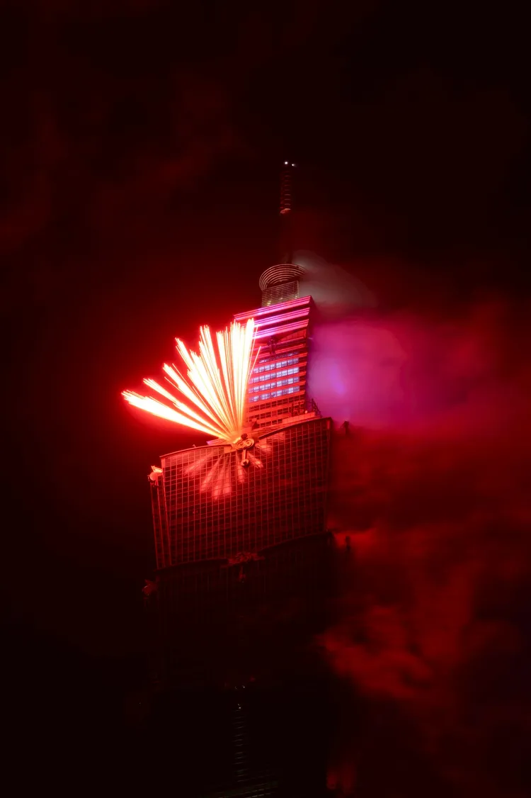 煙火自台北101高樓側面噴射而出，紅色光束在低煙環境中劃破夜空，搭配外牆燈光投影，讓整棟建築宛如一座發光的城市地標。彭欣偉攝
