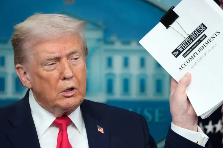 美國總統川普秀出厚厚一疊政績報告。美聯社