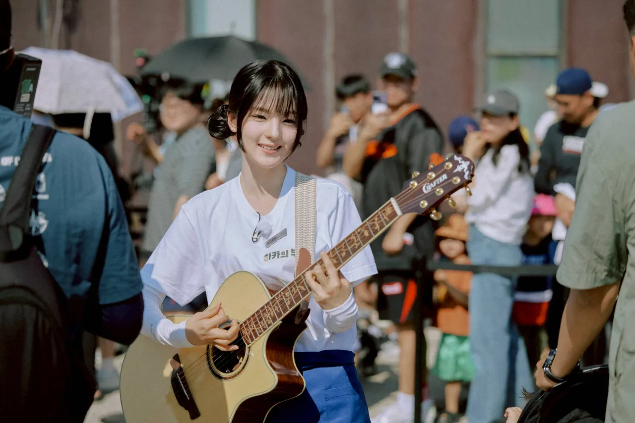 大势新人珪斌背起吉他，现场即兴弹唱，用歌声安抚等候民众。客家电视台提供