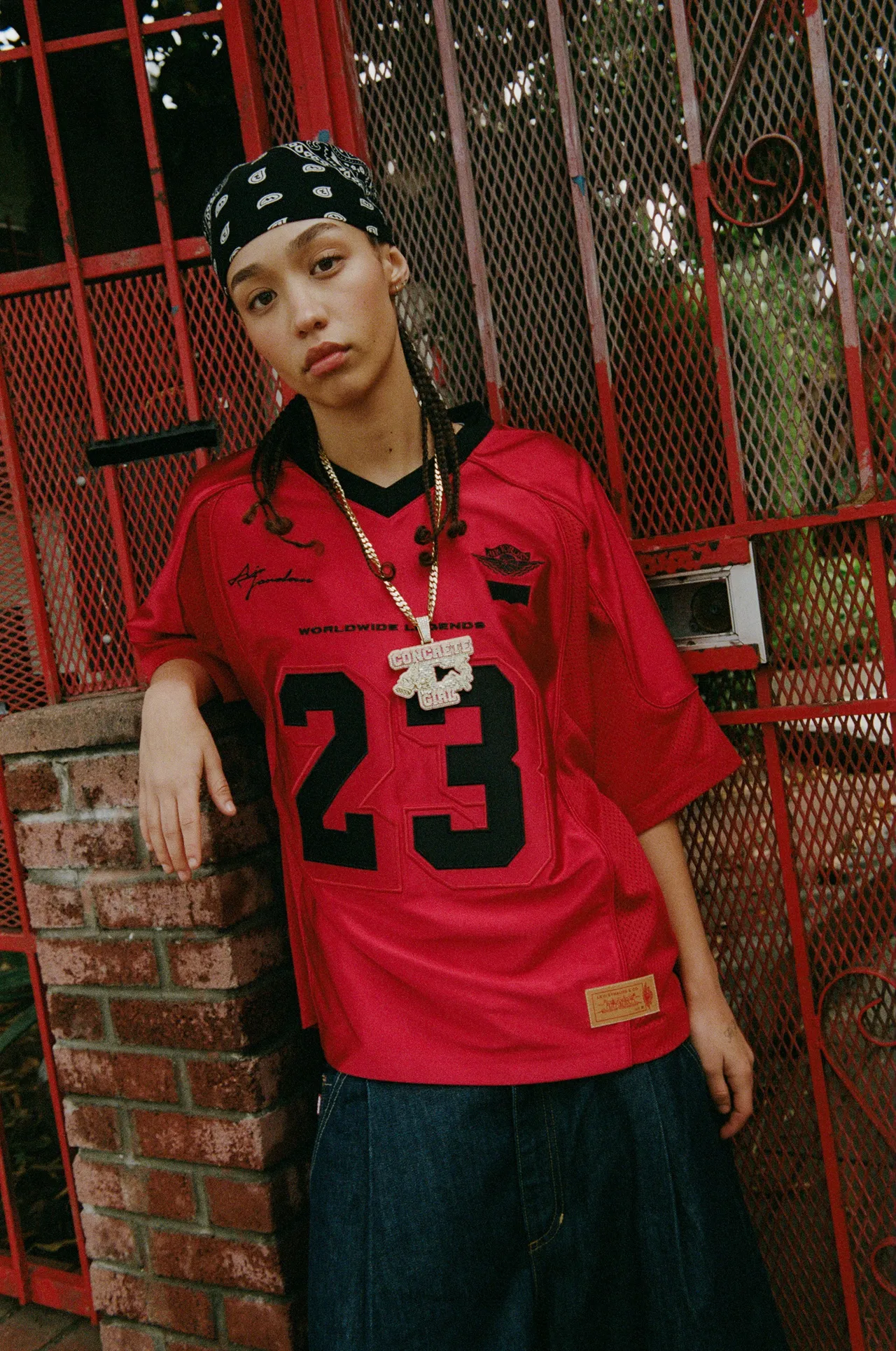 足球球衣採用紅色霧面與亮面拼接設計，細節處加入聯名運動員標籤。品牌提供