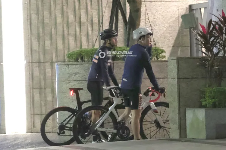 晚間近7點，王少偉（左）和朋友一起騎高檔自行車回到大安區1.76億元豪宅後門，和警衛打招呼。特勤中心攝