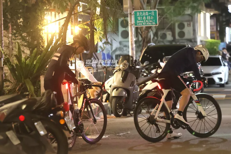 王少偉（左）將「可樂果」COLNAGO自行車牽出餐廳外，檢查車尾燈和龍頭設定。特勤中心攝