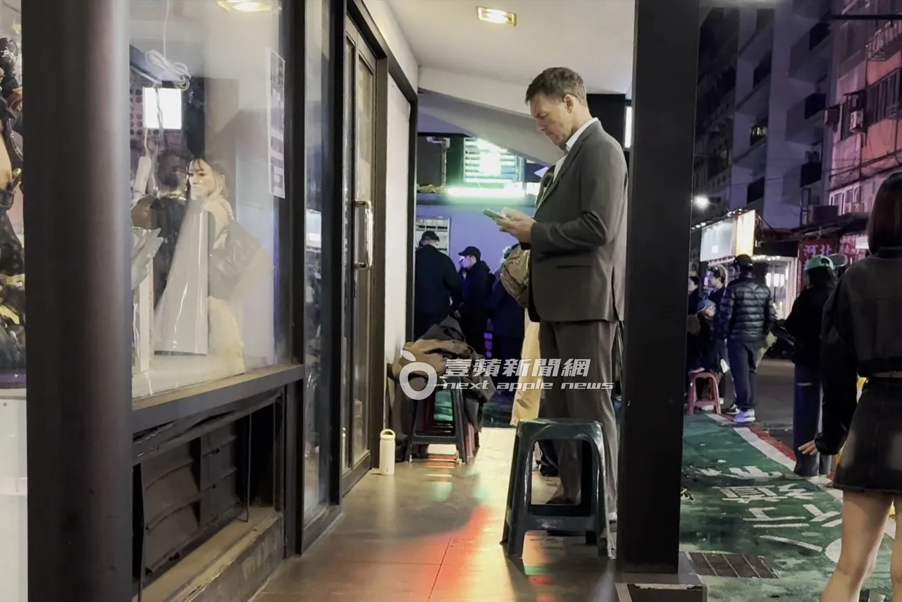 山姆沃辛頓拿起手機看了一會，準備拍攝櫥窗內的大型公仔。特勤中心攝