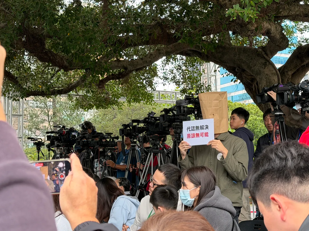 民眾頭戴紙袋於蔣萬安致詞時手舉字牌，寫著「代誌無解決，原諒無可能」。莊偉祺攝