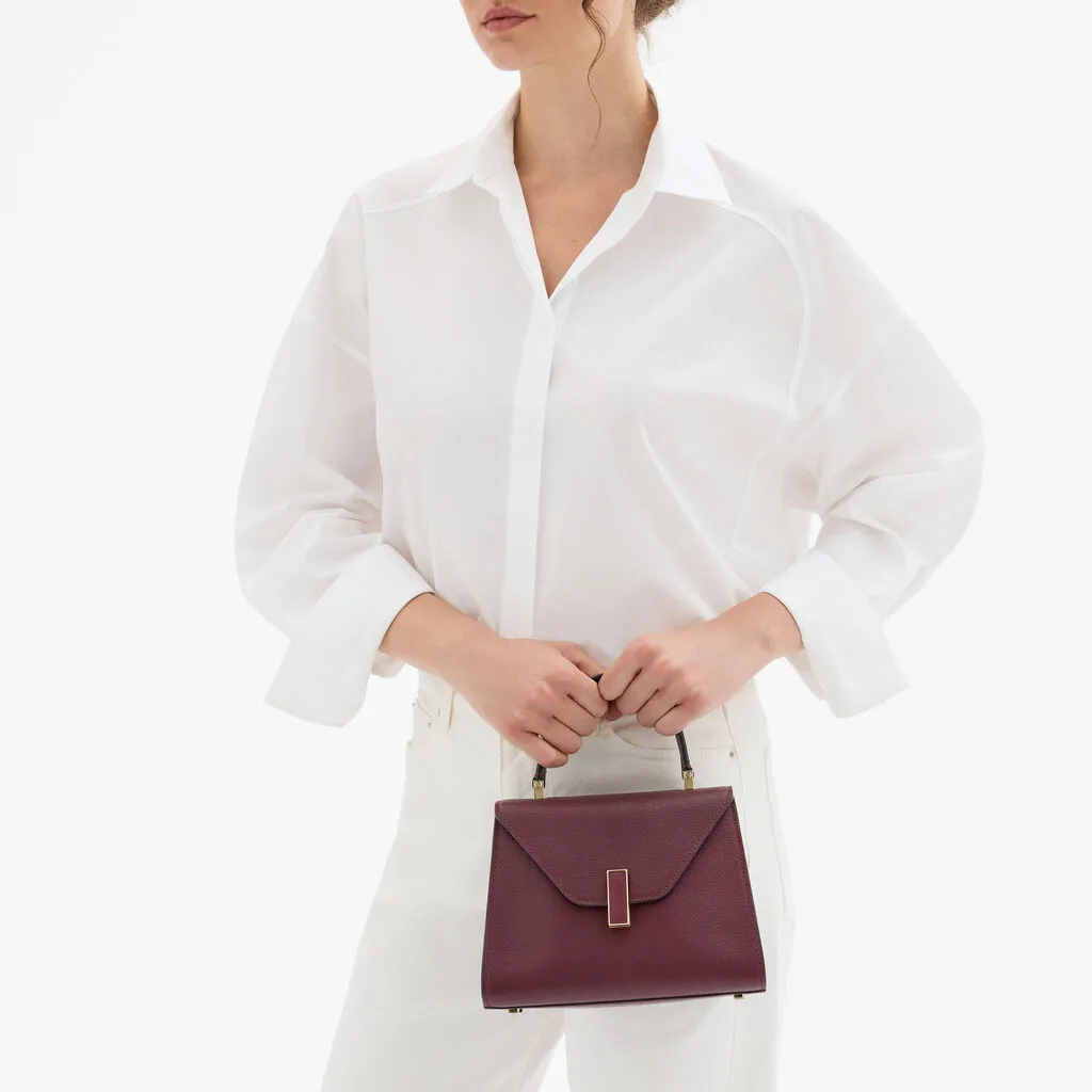 Iside家族系列以標誌性金屬鎖扣與建築感線條搭配莧紫紅色調呈現當代而優雅的節慶風格。品牌提供