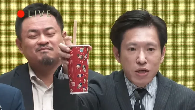 張惇涵舉起奶茶不久，洪申翰突然露出笑容。翻攝自行政院YT