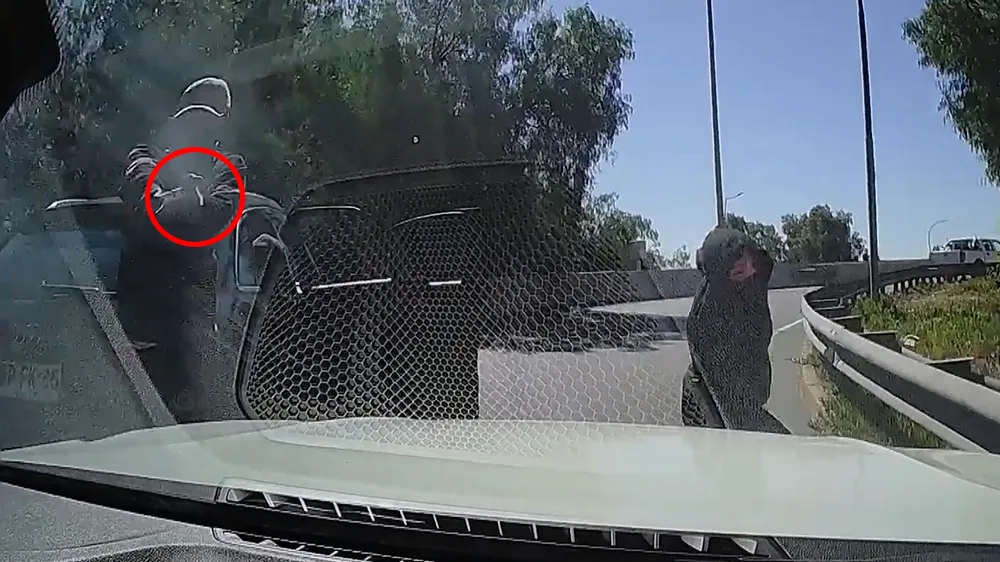 一名搶匪掏槍（紅圈處）瞄準後車，另一人繞到另一側準備行搶。翻攝自YouTube