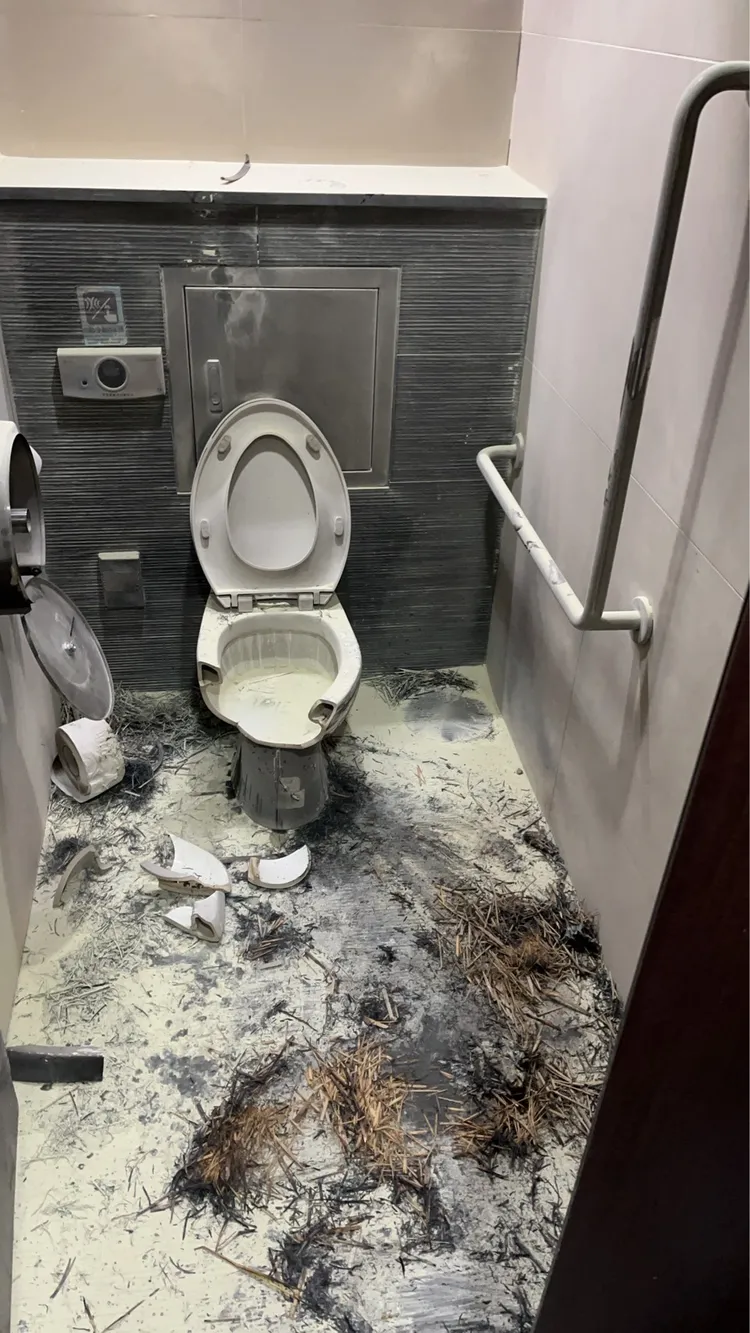 善導寺捷運站男廁內遭縱火後一片慘狀，馬桶被燒毀、紙巾架掉落，現場黑汙一片。翻攝畫面