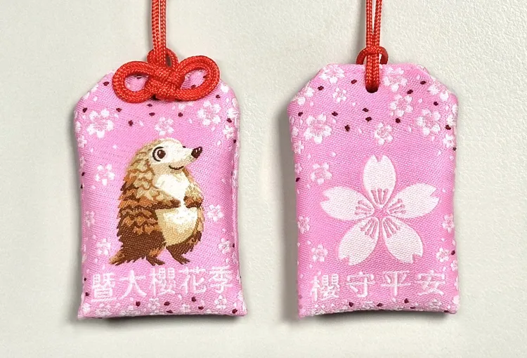 「櫻花季專屬御守」將校園神獸「穿山甲」與嬌嫩櫻花圖騰融入其中，每日限量贈送。暨南大學提供