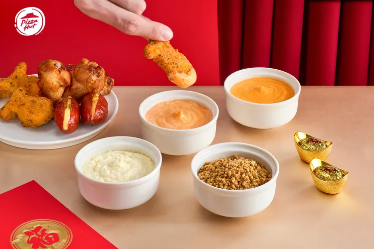 春節限定「一公尺派對盒 好運醬淋」加入明太子醬、義式白醬、切達起司醬及酥香脆粒可搭配。必勝客提供