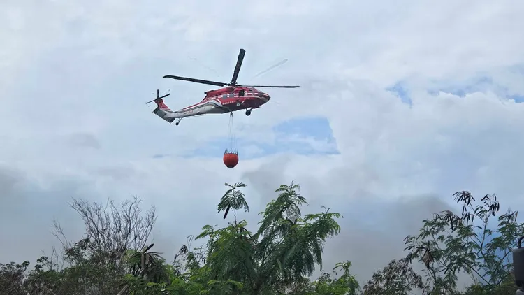 空勤直升機吊掛水袋從空中灑水幫忙滅火。消防局提供
