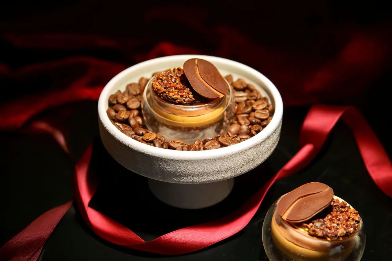 台北萬豪「魔幻巧刻」雙人下午茶，「西西里咖啡巧克力慕斯杯」杯底是66%加勒比巧克力咖啡奶油醬，中層夾入酸甜的檸檬與柑橘奶油餡，頂層覆上帶有清新柑橘與果乾芬芳的64%塔諾里巧克力慕斯，並以黑胡椒可可脆片及咖啡豆造型巧克力點綴。業者提供