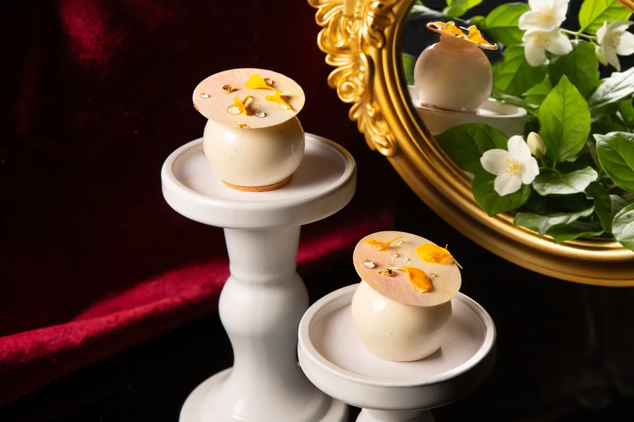 台北萬豪「魔幻巧刻」雙人下午茶，「茉莉白桃柚子白巧克力慕斯」底層是杏仁蜂蜜蛋糕與巧克力脆片，堆疊清甜白桃果泥凍與柚子奇想巧克力奶醬。外層包覆歐帕麗絲白巧克力慕斯。業者提供