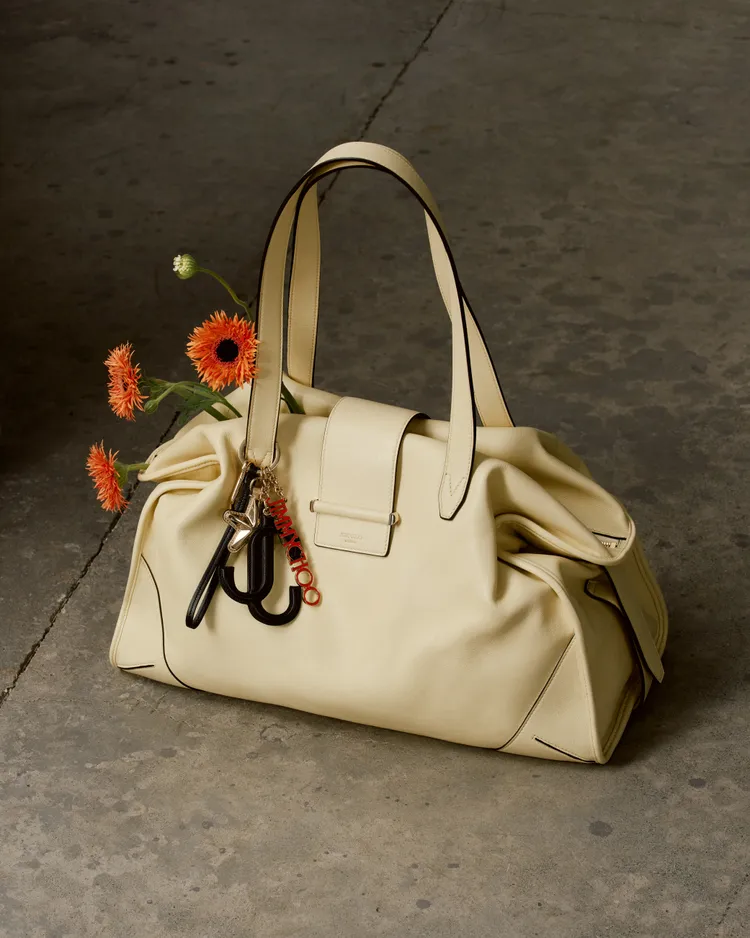 米白色BAR HOLDALL包在手把處點綴品牌金屬字母吊飾。品牌提供