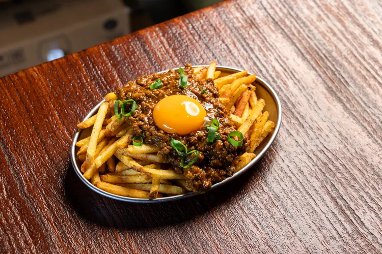 「月見肉末咖哩薯條」以酥脆馬鈴薯條為基底，搭配濃郁乾式咖哩肉末與滑順月見蛋黃，呈現鹹香與濃厚交織的風味層次。臺虎提供