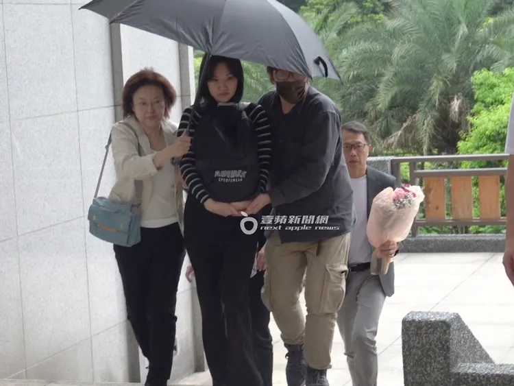 由吳中純的大姐（左）幫忙撐傘，女兒梅嬿翎（中）捧著媽媽吳中純的骨灰罈，腳步十分謹慎。特勤中心攝