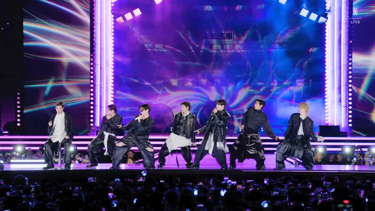 RM（左）腳受傷，坐在椅子上表演。翻攝Netflix