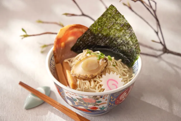 「日式鮑魚雞白湯拉麵」湯頭選用老母雞與豚骨歷經四小時以上慢火細燉，搭配彈牙拉麵與鮮美鮑魚，每一口都展現出極致層次。台北喜來登大飯店提供