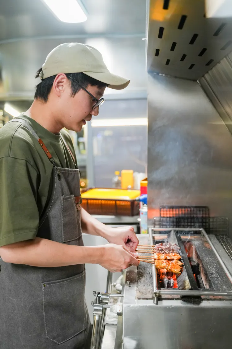 Sean在水冷式烤爐上精準翻動食材，一股炭火燻香撲鼻而來。田欣雲攝