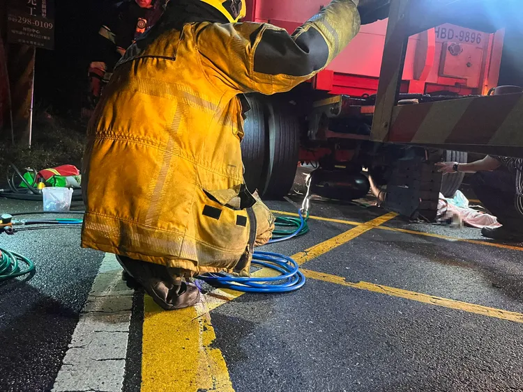 消防人員動用重型救援推頂器材，將聯結車頂起救出女騎士，確認已明顯死亡。民眾提供