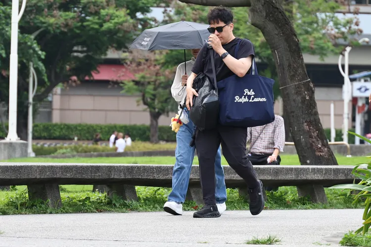 朱海君遠遠看到媒體就先用傘遮擋臉。攝影中心攝