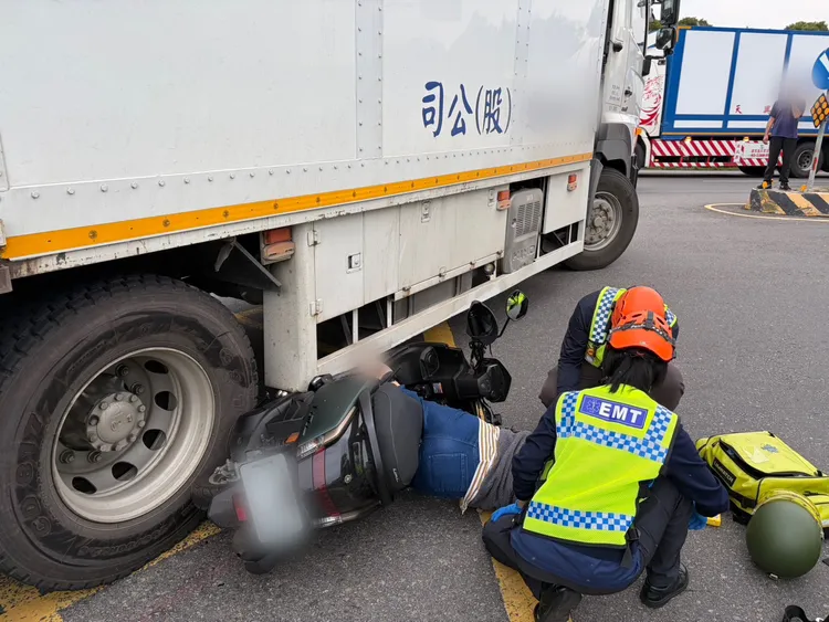 林姓女騎士雙腿卡在大貨車輪下，消防人員將她救出。民眾提供