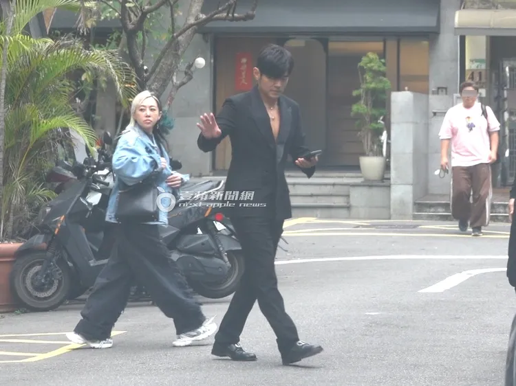 周杰倫（右）邊看手機邊與粉絲揮手打招呼。特勤中心攝