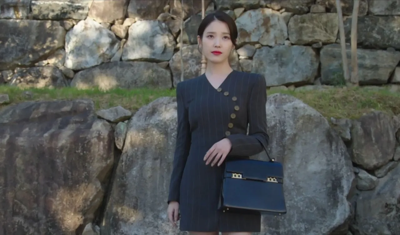 IU以直條紋西裝洋裝搭配黑色款Tempête MM。翻攝Disnay+