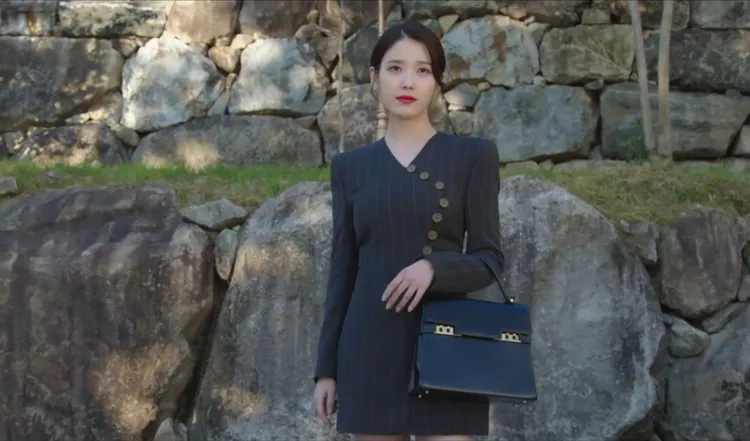 IU以直條紋西裝洋裝搭配黑色款Tempête MM。翻攝Disnay+