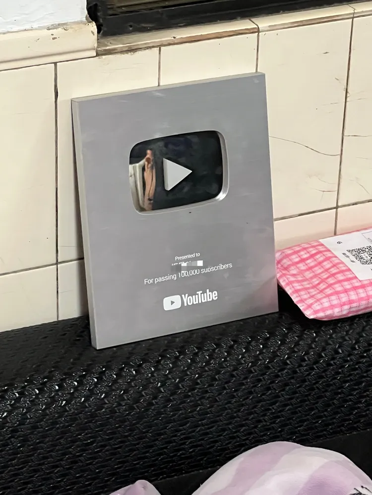 廖嫌客廳擺放著YT頻道達到10萬訂閱者的銀色獎牌。翻攝畫面