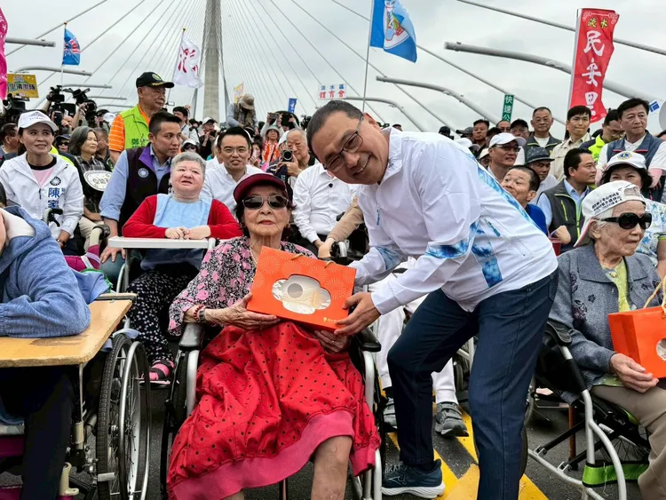 侯友宜向阿嬤致意，並致贈淡江大橋意象燈飾祝福。民政局提供