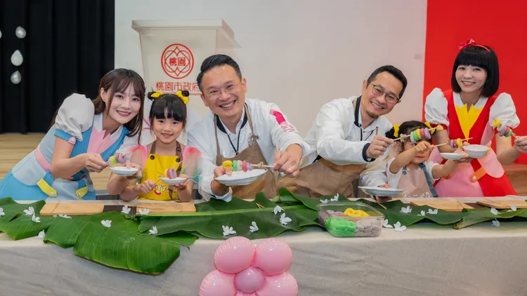 桃園市副市長蘇俊賓與雲朵姐姐、草莓姐姐及2名小女童，共同製作串起彩色版客家傳統點心「牛汶水」。客家局提供