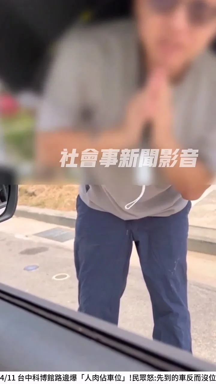 人肉佔位的撐傘男還雙手合十，拜託對方不要來停該停車位。翻攝「社會事新聞影音」
