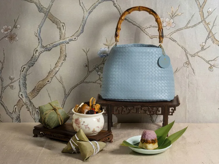 「南洋風情食趣組」配上淺藍編織竹節包，將四顆異國美粽與「巴生肉骨茶」湯包優雅封存，盡顯夏日涼意，每組1588元。台北遠東香格里拉提供